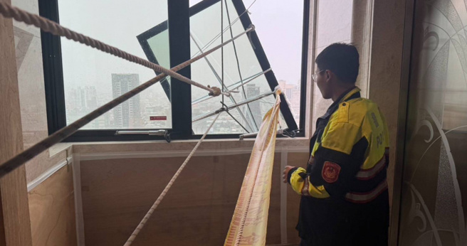 三重大同南路一處社區23樓的走道窗戶遭到強風吹歪搖搖欲墜，警方獲報即刻救援幫忙綑綁固定。（圖／翻攝畫面）