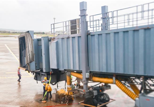 桃园国际机场31日受康芮颱风影响，航班取消逾200班次。下午桃园机场空侧风速达83节，远过空桥防护作业标准（55节以上绑桥），地勤人员连忙上机坪固定空桥。（陈麒全摄）