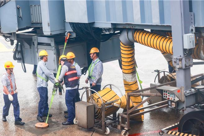 桃园国际机场31日受康芮颱风影响，航班取消逾200班次。下午桃园机场空侧风速达83节，远过空桥防护作业标准（55节以上绑桥），地勤人员连忙上机坪固定空桥。（陈麒全摄）