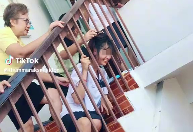 泰国一名女学生开学日，因为偷看楼下的男同学，意外将头卡在楼梯护栏缝隙中。（翻摄TikTok@thammaraksahaidon）