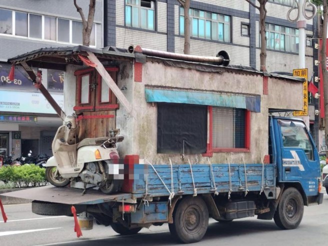 网友在路上看到移动住宅，货车后方载着砖瓦房，有门窗还有屋檐，甚至上面还有一辆机车。（翻摄爆料公社）