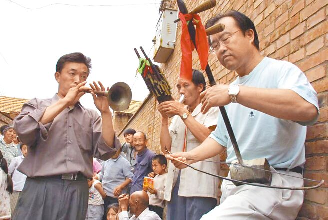 大陸非物質文化遺產保護專家田青拉著胡琴，與大陸民間藝人在街頭鼓樂齊鳴。（中華翰維文化推廣協會提供／蔡明亘台北傳真）