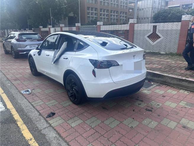 台中市北屯区1国小惊传正中午在学校驻车弯发生恶煞砸车惊悚事件，白色特斯拉车身、车窗、后照镜等多处损毁。（民眾提供／冯惠宜台中传真）