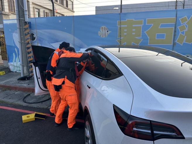 白色特斯拉因不明原因，直衝撞上牆壁，導致車頭凹陷毀損，讓海巡人員傻眼。（蕭宥彤翻攝）