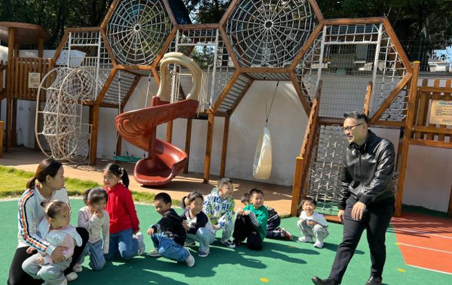 幼稚园负责人柯鑫和幼师一起，带着孩子们在操场上嬉戏，处处欢声笑语。（图/金津提供）