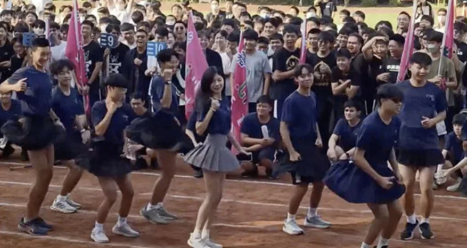 一名穿短裙的长髮女子混在学生中跳三振舞，亮丽外型与美腿成为焦点，没想到身分竟是英文老师。(图／影片截图)