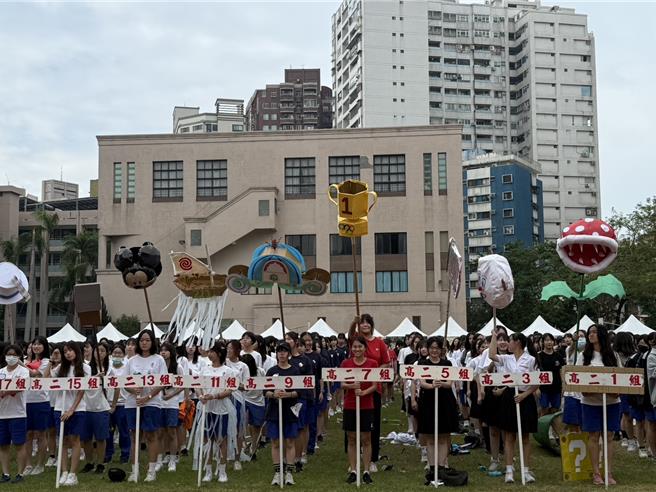 雄女学生举出班旗，以及自制的标志性班徽。（纪爰摄）