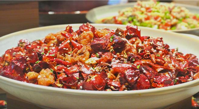 「山城辣子鸡」拌入新一代辣椒、灯笼辣椒、青红花椒、藤椒油、酒鬼花生等香料一同入锅翻炒，形形色色的辛香料碰撞出鲜辣纯香。(陈韵萍摄)