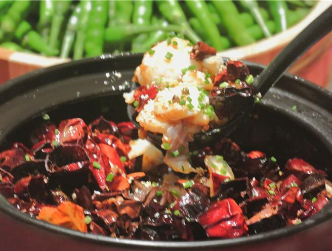 「沸腾时令现捞鱼」可近距离观赏到主厨浇淋辣油的桌边「食」境秀，香料鱼淋上热油后的诱人香气，鱼肉的鲜嫩入味，同时满足视觉、嗅觉与味觉。(陈韵萍摄)