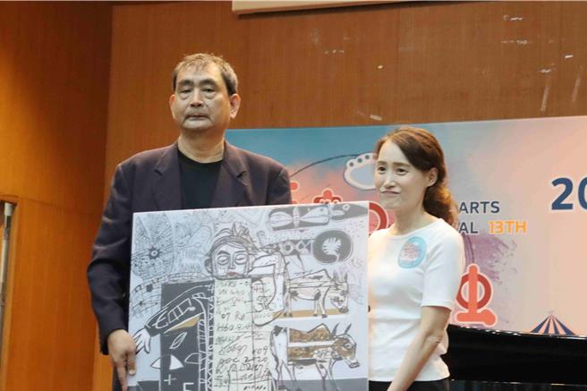 戴明德（左）今捐赠作品《洞穴画情节》给学校，由嘉大主秘林芸薇代表受赠。(吕妍庭摄)