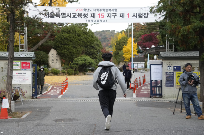 南韩「大学修学能力测验」（修能测验）14日登场，全国52万多名考生在1200多处考场同步应试。图为考生一早步入首尔一所高中设置的考场背影。（美联社）