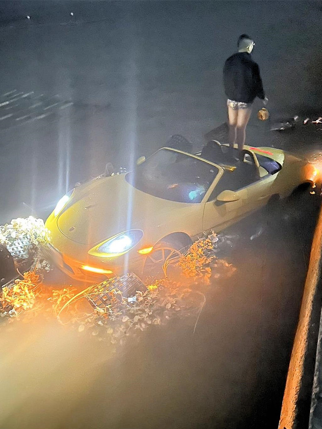 保时捷敞篷跑车车头卡着装篮蚵壳，疑似一起被跑车撞进海里，驾驶站在车上等候救援。(读者提供／吕妍庭嘉义传真)