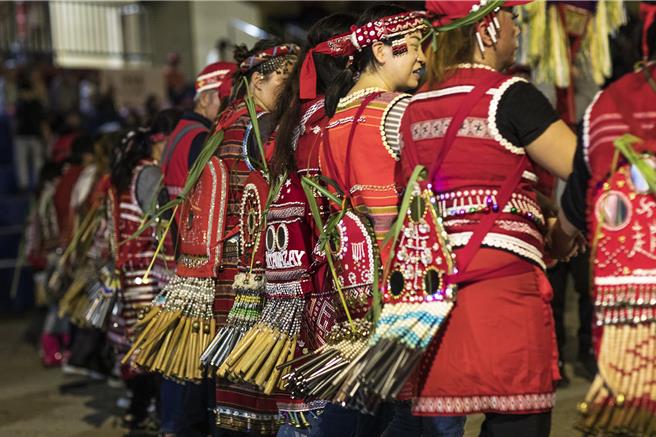 五峰乡赛夏族巴斯达隘祭典「矮灵祭」15日晚「迎灵」，赛夏族人穿红色传统服装，腰缠成排的竹管或铁管，身体前后摇摆发出竹击和铁管声响，缓步绕着祭场，彻夜迎灵舞蹈充满神秘色彩。（罗浚滨摄）