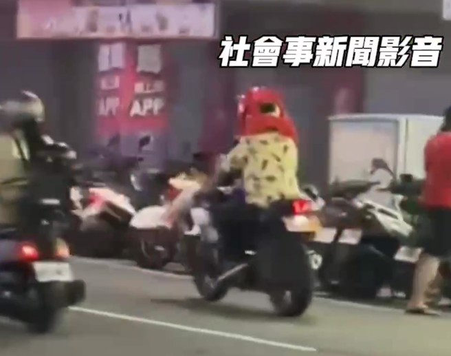一名机车驾驶竟将塑胶椅子挂在颈部以上，行经新北市三重区自强路一段。（翻摄社会事新闻影音）