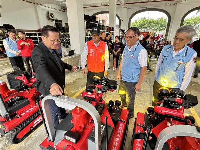 消防署長蕭煥章(左前)向與會嘉賓介紹救災機器人之各項功能，期結合高科技救災設備到位，未來能大幅度降低消防人員救災時之風險。(于家麒攝)