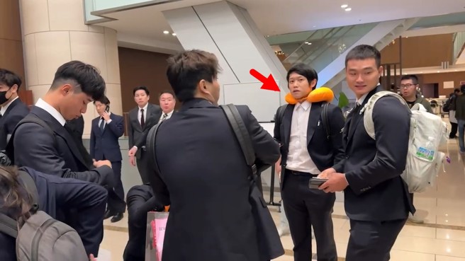 中华队成员在饭店大厅等候分房，大家清一色的西装，而陈冠宇的橘色靠枕相当抢眼。（郭先扬摄）