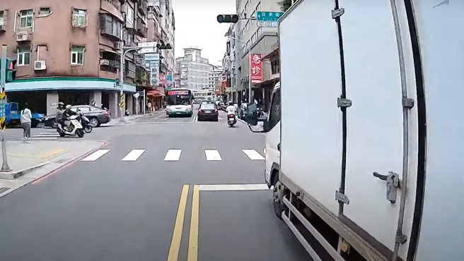 有骑士发现路口停1辆打着双黄灯的小货车，他忧有行人要通过便减速，果然，就有女行人在等待过马路。（图／翻摄自WoWtchout - 地图型行车影像分享平台）