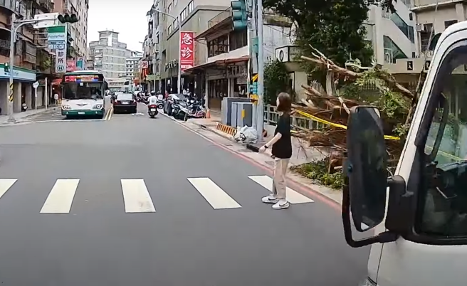 有骑士发现路口停1辆打着双黄灯的小货车，他忧有行人要通过便减速，果然，就有女行人在等待过马路。（图／翻摄自WoWtchout - 地图型行车影像分享平台）