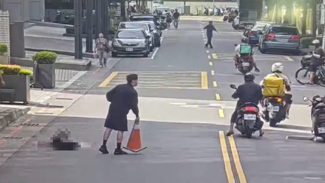 被害人倒卧道路，路人持交通锥协助交维。（图 / 刘咏韵翻摄）