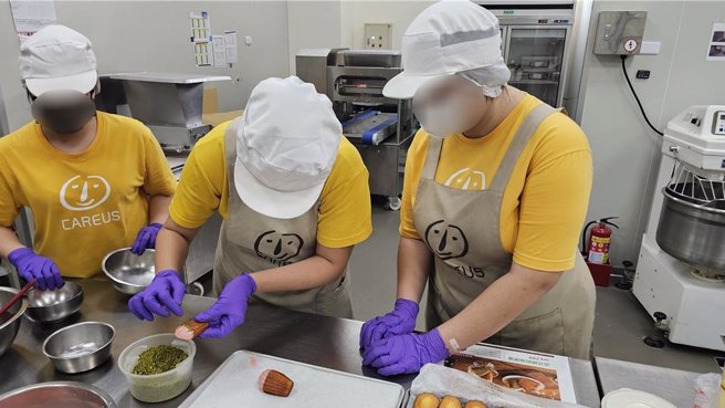 庇護員工跟著就服員（中）學習裝飾技巧。（林雅惠攝）