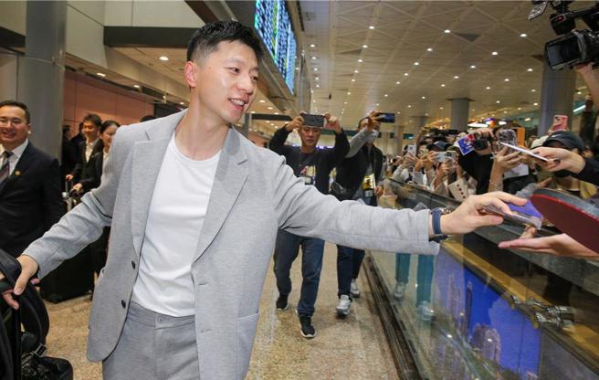 马龙步出接机大厅时受到欢迎，他亲切挥手致意，还特别从口袋拿出北京体大的磁性冰箱贴小礼物送给球迷。（陈麒全摄）