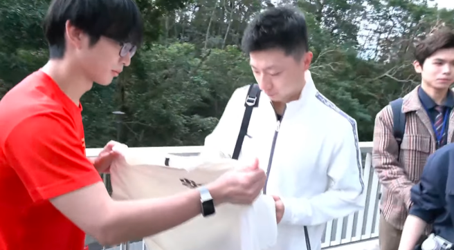 大陆桌球名将马龙28日随陆生团参访政治大学，不少学生拿出衣服、球拍带抢签名。 (截自中时新闻网直播)
