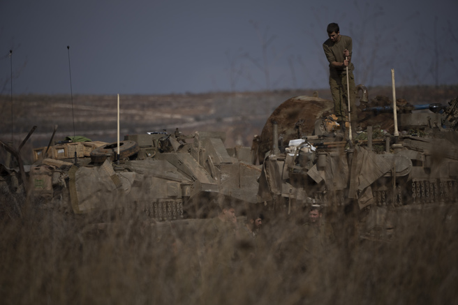 一名以色列士兵在以色列-黎巴嫩邊境附近地區的一輛裝甲車頂部工作。（圖／美聯社）