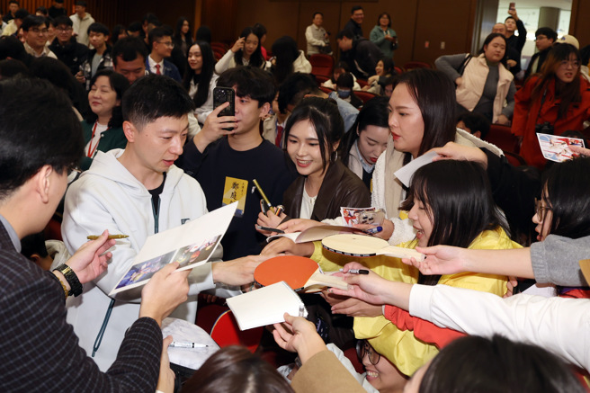 大陆桌球名将马龙（左，白衣者）近日跟随陆生团访台，29日前往文化大学进行交流，并与我国退役桌球名将蒋澎龙与巴黎奥运国手陈思羽切磋球技，上演奥运层级的交流赛。散场后离去前一堆学生涌上去索取签名。（邓博仁摄）
