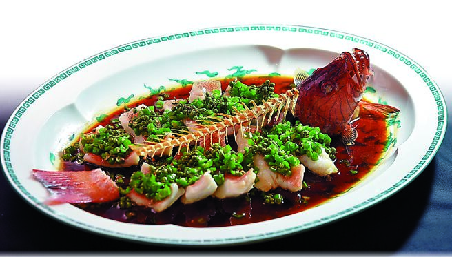 〈青辣汁深海东星斑〉是许凡独创「青辣」味型，选重逾1公斤的澎湖野生东星斑剔骨片肉，淋上鸡油清蒸，出笼后淋上以汉源新鲜青花椒、蒜末、过油青辣椒、海天鲜酱油煮成的「青椒汁」，再淋上藤椒油激发椒香，青花椒中的柠香四溢、清新中带麻韵。图／姚舜