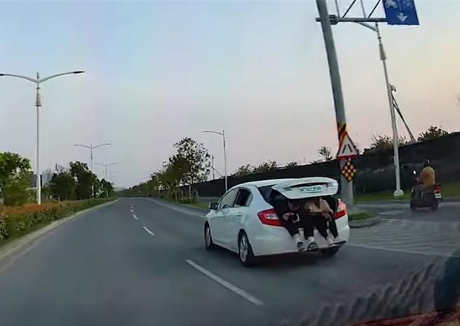 高雄楠梓民眾拍下危险驾驶短片，一辆轿车的后车厢上坐着两个人，双腿挂于车外。（摘自Youtube：wowtchout网页／林瑞益高雄传真）