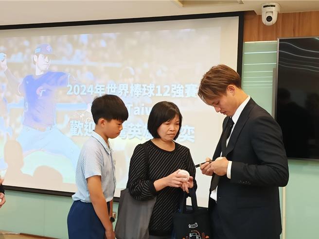 张毅抽出20名幸运儿，并为球迷在棒球上签名。（叶静美摄）