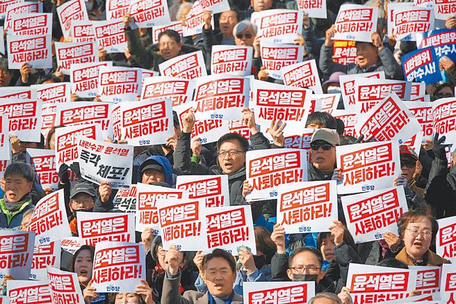 首尔民眾4日举着抗议标语牌，谴责韩国总统尹锡悦突然宣布戒严令，并要求他辞职。（路透）