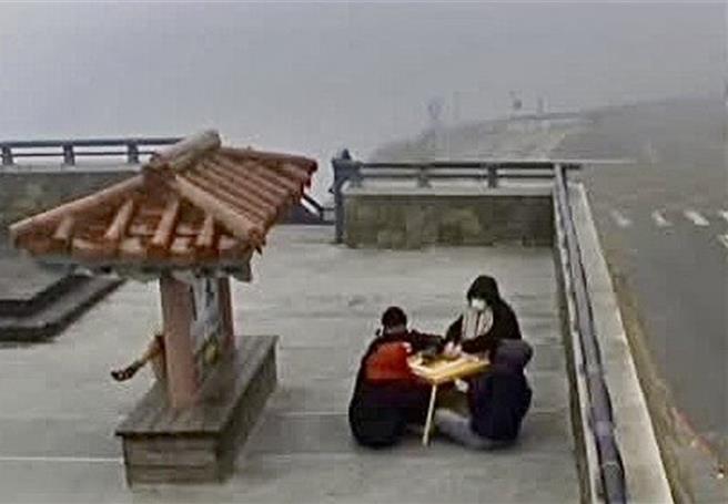 包围小方桌打麻将的4个人，将桌子移至武岭亭前继续奋战。（翻摄公路局合欢山武岭亭即时影像／杨静茹南投传真）