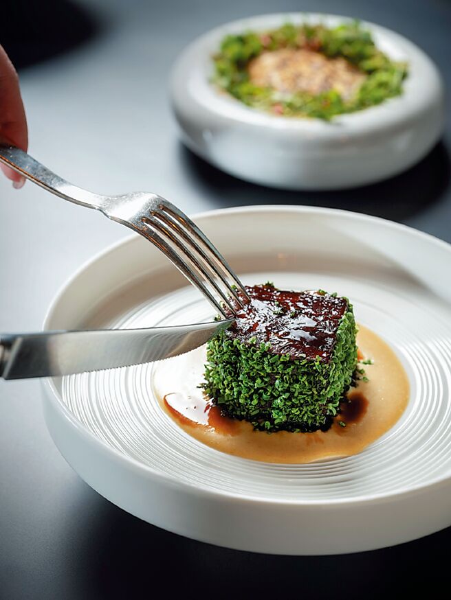 「慢炖和牛牛颊、古冈佐拉乳酪、烤蕈菇、玉米糕、迷迭香、虾夷葱」中，肉质软嫩的和牛牛颊，是以蔬菜与牛肉高汤炖煮五小时，塑以雅致的方块造型，外层裹以新鲜虾夷葱，搭配带着浓郁乳香且甘醇的古冈佐拉乳酪酱汁，迷迭香则添以一抹清亮，丰润展演专属冬日的绝美滋味。图／台北文华东方酒店