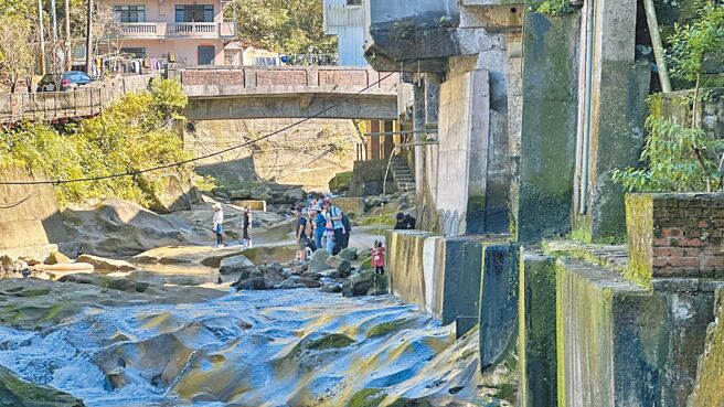 新北市石碇区石碇老街一带建筑老旧，早期规画让许多住户将污水管直接向外延伸，并将水排放至崩山溪中，形成民眾在溪边戏水，一旁却有不明污水从管道中宣泄而下的场景。（贺培晏摄）