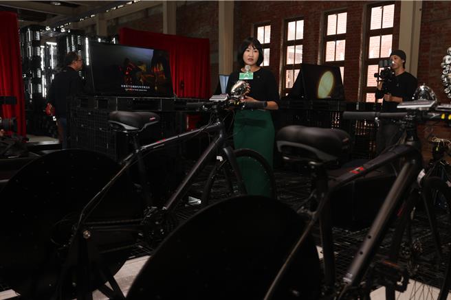 策展人方叙洁（中）介绍展区的自行车发电装置，民眾可体验充一度电，需要提供多少动能，进而反思能源的珍贵。（文化部提供／李怡芸台北传真）