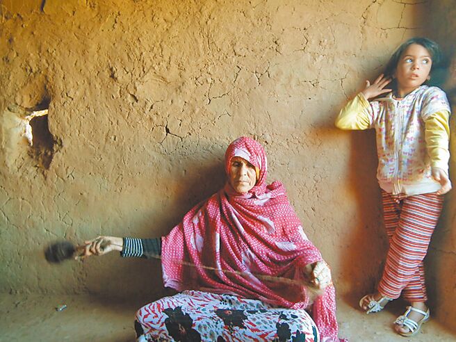 面對鏡頭，模特兒般熟練地整理羊毛線的芭荷妲，曾孫女娜蒂雅在旁玩耍。（蔡適任攝）