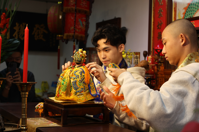 祖师爷冬季换袍大典由国立臺湾戏曲学院学生秦朗(左)与余铭贤(右)为祖师爷换袍。（臺湾戏曲学院提供）