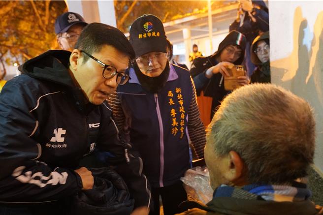 新北市启动「街友与独居长辈低温关怀行动」，今（13）日晚间由副秘书长张其强率领社会局、消防局、警察局、板桥区公所及夜访志工队和外展中心，前往板桥区介寿公园探视慰问街友，提供外套、毛帽、暖暖包及泡麵等御寒物资，并劝导入住中途之家或安心旅馆避寒。（新北社会局提供）