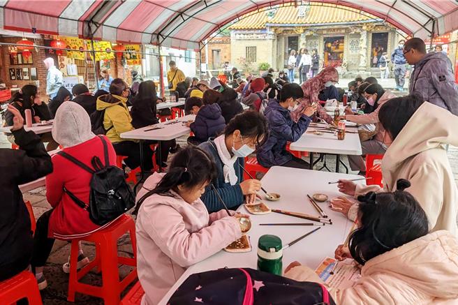县府交旅处14日在北埔老街举办「达人带逛及柿染体验活动」，超过百位游客在慈天宫庙前广场体验手作柿染，制作独一无二的零钱包。（新竹县政府提供／罗浚滨新竹传真）