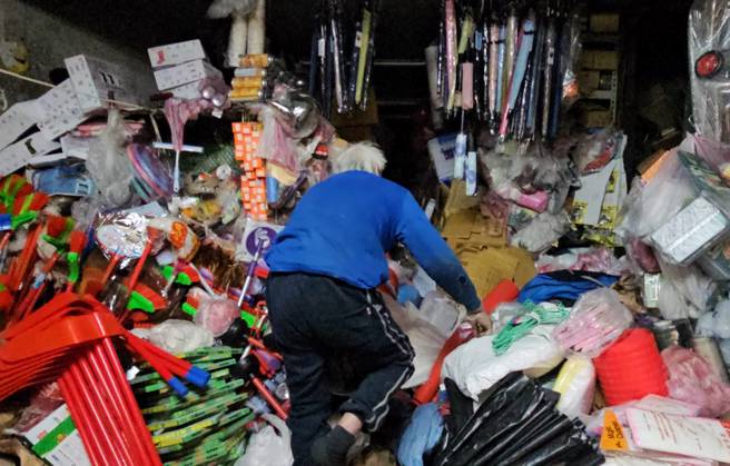 余老板爬进店里找商品。（记者游定刚拍摄）