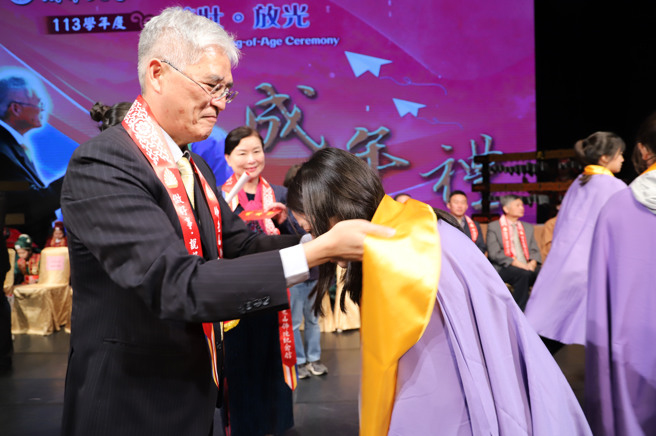 南华大学于佛光山佛陀纪馆举办成年礼，高俊雄校长(左)为学生披巾行「再加礼」仪式。(照片/南华大学提供)