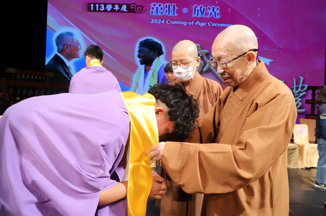 南华大学于佛光山佛陀纪馆举办成年礼，董事长慈惠法师(右)为学生披巾行「再加礼」仪式。(照片/南华大学提供)
