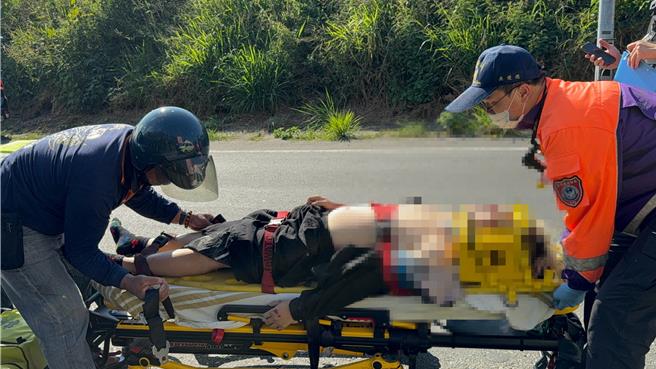 机车骑士被热心义消(左)及救护人员送上救护车。(吕妍庭摄)