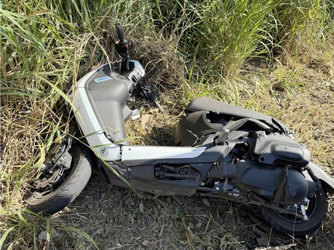 机车骑士卡在货车下，机车则摔进路边草丛。(吕妍庭摄)