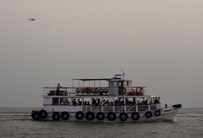 印度海軍一艘快艇18日下午高速衝撞一艘載有上百人的觀光渡輪，釀成13人死亡。圖為意外發生後，一架直升機飛越附近另一艘渡輪上空，搜尋生還者。（路透社）