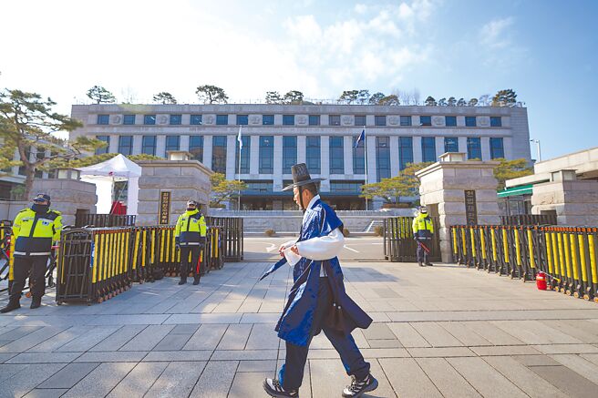 一名身穿韩国传统服装的游客17日走过韩国首尔宪法法院前。（美联社）