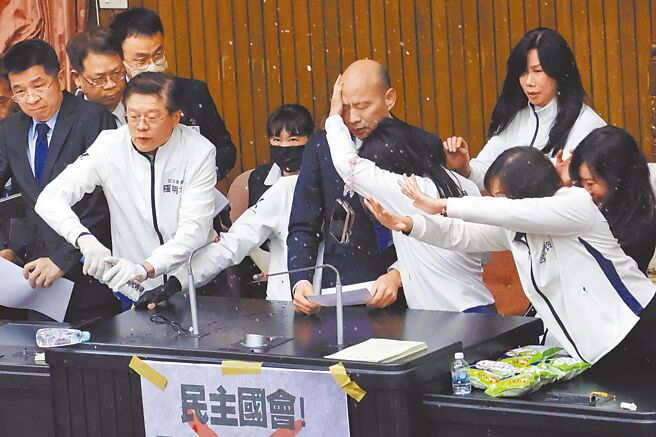 立法院会20日排审选罢法等案，立法院长韩国瑜（上排中）约于11时50分在国民党立委护送下站上主席台，宣布採举手表决，遭到民进党立委邱议莹泼水。 （邓博仁摄）