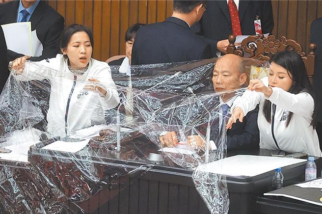 立法院会20日处理选罢法、宪诉法及财划法修正案，爆发蓝绿立委衝突，国民党立委徐巧芯（左）、张嘉郡（右）在立法院长韩国于前拉起保鲜膜，让议事进行顺利。（本报资料照片）