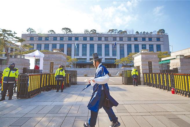 一名身穿韩国传统服装的游客17日走过韩国首尔宪法法院前。（美联社）